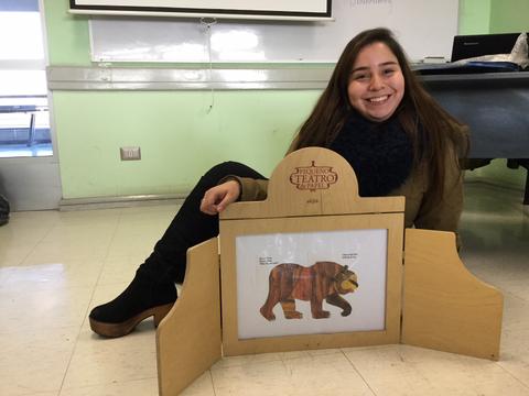 Una joven sonriente sostiene un cuadro con la ilustración de un oso, rodeada de un marco de madera.