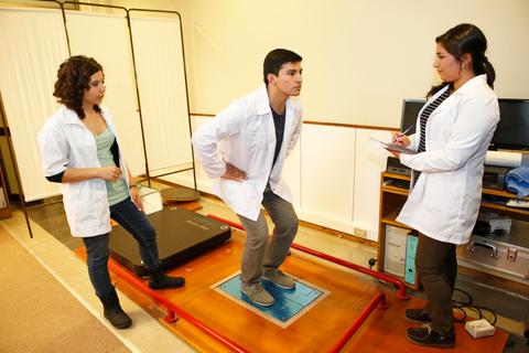 Un grupo de personas en un entorno clínico están realizando un ejercicio de evaluación física.