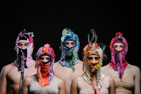 Cinco personas con máscaras coloridas y decoradas posan en un fondo oscuro.