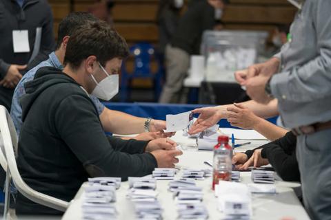 Personas participando en un proceso de votación en un ambiente organizado.