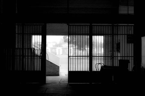 Una entrada oscura con rejas que da a un área iluminada.