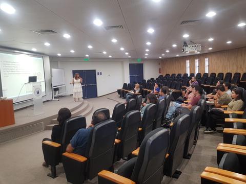 Una sala de conferencias con un presentador y un público atento.