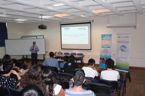 Una presentación en un aula con un ponente frente a una audiencia de estudiantes.