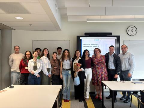 Grupo de estudiantes posando felizmente después de una presentación en una sala de clases.