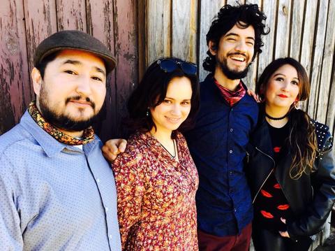 Cuatro personas sonrientes posan juntas frente a una pared de madera.