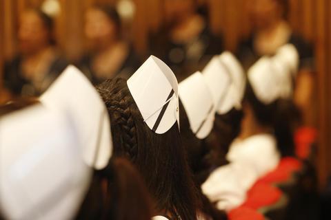 Una fila de estudiantes con gorros blancos en un evento formal.
