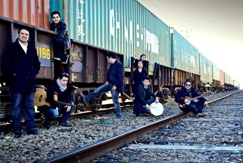 Siete personas posan junto a un tren de carga en un paisaje urbano.