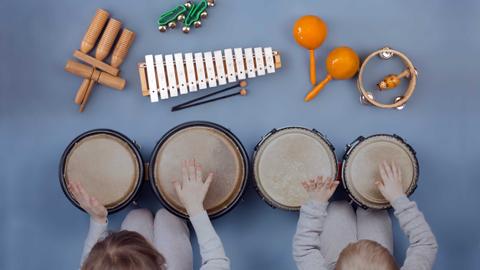 Dos niños tocan instrumentos musicales en un entorno divertido.