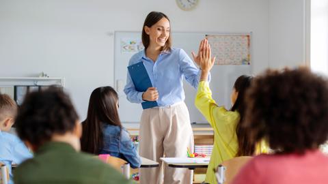 Una profe sonriente interactúa con sus estudiantes en una sala de clases.