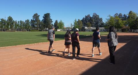 Un grupo de personas caminando por una pista de atletismo en un día soleado.