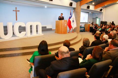 Un evento institucional se lleva a cabo en un auditorio con una audiencia atenta y una presentación del orador frente a un podio.