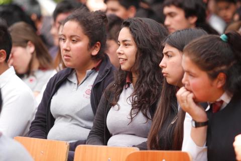 Un grupo de jóvenes sentados en un evento, mostrando diferentes expresiones en sus rostros.