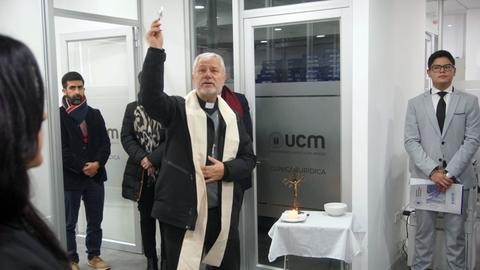 Un sacerdote bendice un espacio en una clínica mientras varias personas observan.