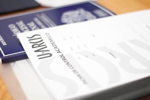 La imagen muestra documentos académicos sobre una mesa.