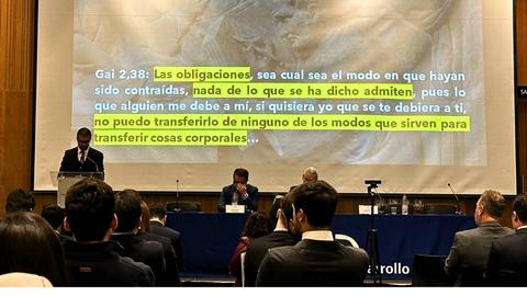 Un hombre habla frente a un proyector que muestra un texto sobre las obligaciones y su transferencia.