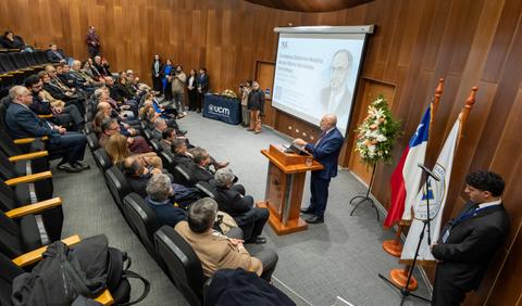 Un evento académico en el que un expositor está hablando frente a una audiencia en una sala equipada.