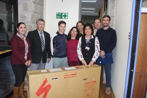 Un grupo de personas sonrientes posando junto a una caja grande en un interior de oficina.