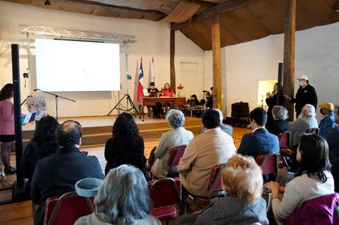 Una presentación en un salón con personas sentadas y un proyector en la pantalla.