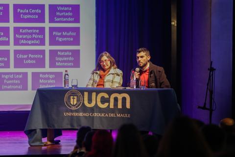 Una conferencia en la Universidad Católica del Maule con dos oradores en el escenario.