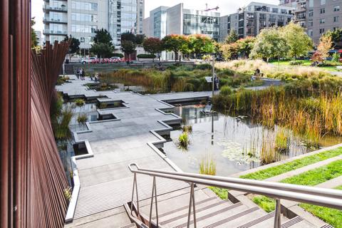 Una vista de un parque urbano con estanques y vegetación en un entorno moderno.