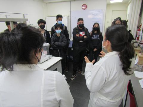 Un grupo de estudiantes escucha atentamente a una instructora en un laboratorio.