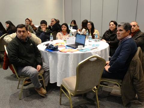 Una reunión de varias personas sentadas alrededor de una mesa en un salón.