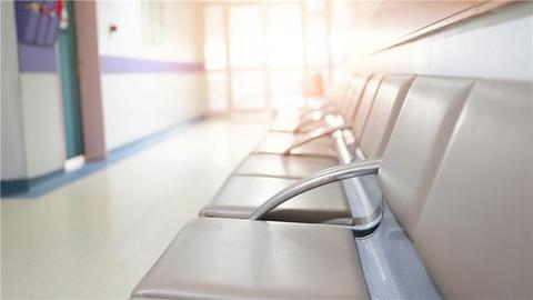 Una sala de espera en un hospital con sillas vacías y luz natural que entra.