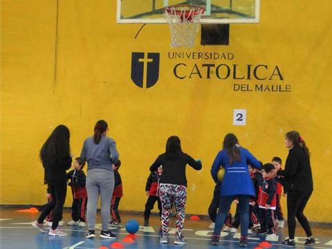 Un grupo de niños y adultos juegan y realizan actividades deportivas en un gimnasio escolar.