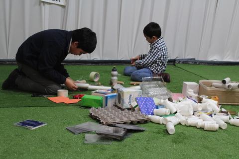 Dos niños están construyendo un proyecto con materiales reciclados en un ambiente de aprendizaje.