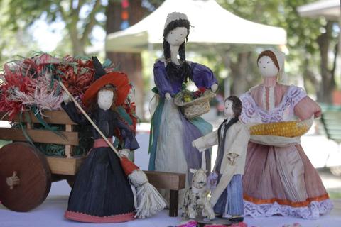 La imagen muestra figuras artesanales de personas vestidas con trajes tradicionales, acompañadas de una carreta decorativa.