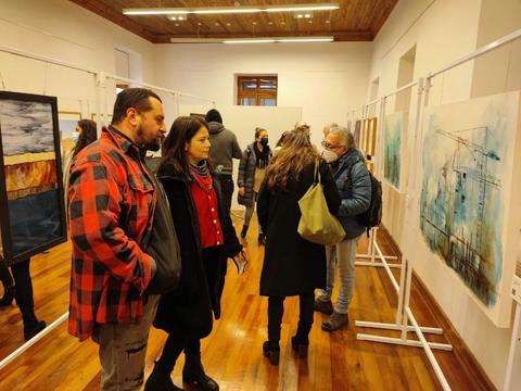 Un grupo de personas observa obras de arte en una exposición.