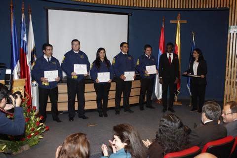 Un grupo de personas en un acto de entrega de certificados en una ceremonia formal.