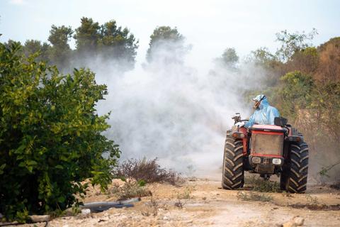 Un agricultor utiliza un tractor para rociar pesticidas en un campo.