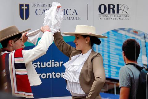 Una pareja baila en trajes tradicionales mientras sostienen un pañuelo en un evento cultural.