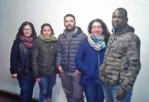 Grupo de cinco personas posando junto a una pared blanca.