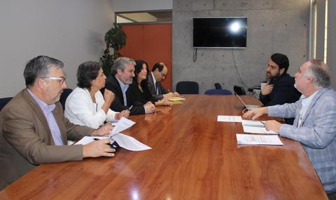 Una reunión de varias personas alrededor de una mesa de madera en un ambiente profesional.