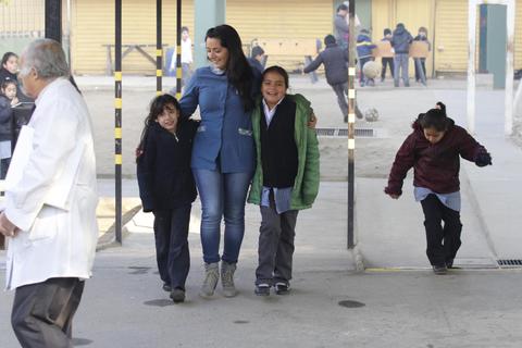 Un grupo de niños felices camina junto a una mujer en un lugar al aire libre.