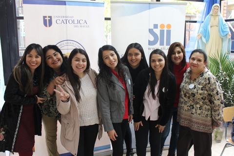 Un grupo de mujeres sonrientes posando juntas en un evento en la universidad.