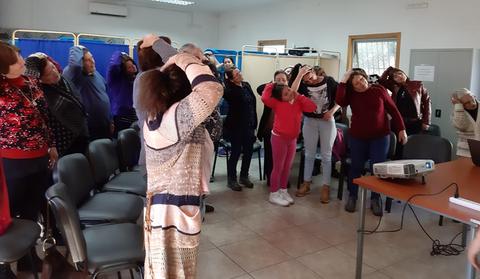 Un grupo de personas mayores realizan ejercicios de estiramiento en un salón.
