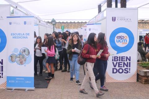 Un grupo de estudiantes se dirige hacia una feria educativa con varios stands informativos.