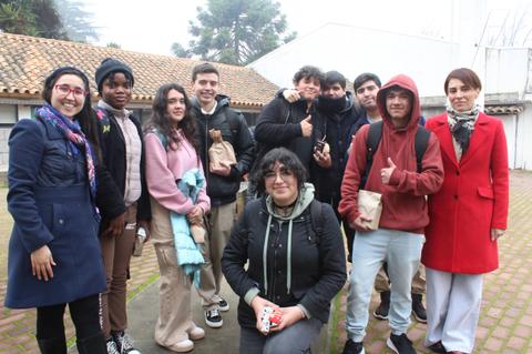 Grupo de jóvenes posando juntos al aire libre en un día nublado.