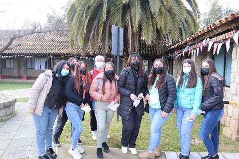 Grupo de jóvenes posando en un parque con árboles y decoración colorida.