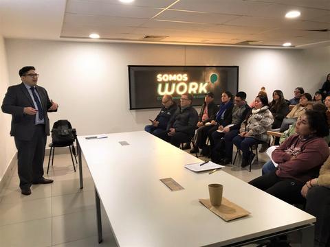 Una charla motivacional donde un exponente habla frente a un grupo de personas atentas en una sala.