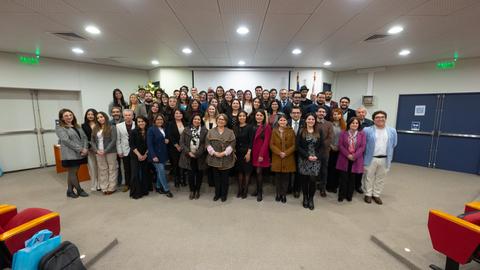 Un gran grupo de personas posa juntas en un auditorio durante un evento.