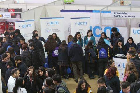 Un grupo de estudiantes se reúne en un stand de la Universidad Católica del Maule durante una feria educativa.