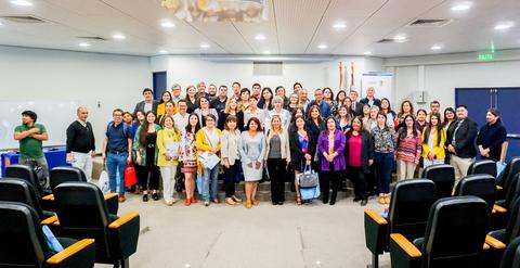 Un grupo grande de personas posando juntas en un auditorio.