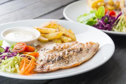 Plato que incluye filete de pescado acompañado de papas fritas y ensalada.