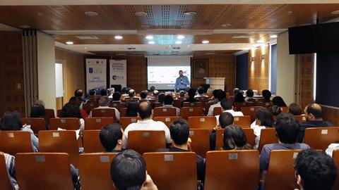 Una conferencia con un ponente frente a una audiencia en una sala de conferencias.