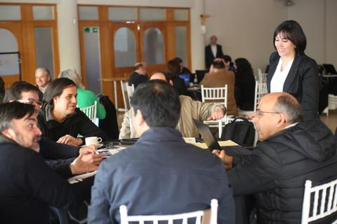 Un grupo de personas se reúne en una mesa para discutir y colaborar en un ambiente de trabajo.