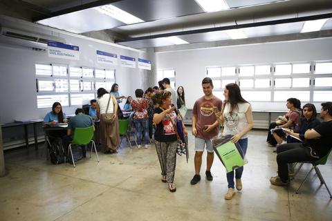 Un grupo de estudiantes interactuando en un aula con mesas y sillas.